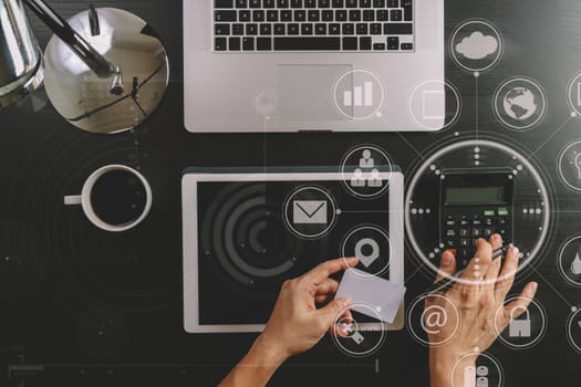 Internet shopping concept.Top view of hands working with calculator and laptop and credit card and tablet computer on dark wooden table background with Vr diagram