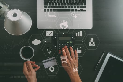 Internet shopping concept.Top view of hands working with calculator and laptop and credit card and tablet computer on dark wooden table background with Vr diagram