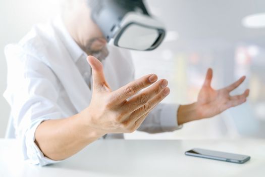 businessman wearing virtual reality goggles in modern office with Smartphone using with VR headset 