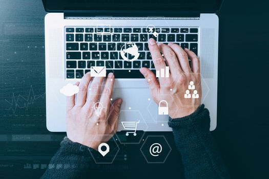 top view of businessman typing keyboard with laptop computer on wooden desk in modern office with virtual reality icon diagram   