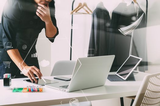 Fashion designer talking mobile phone and using laptop with digital tablet computer in modern studio with VR icon diagram