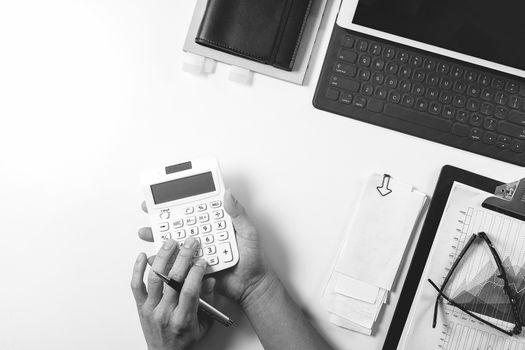 top view of businessman hand working with finances about cost and calculator and latop with mobile phone on withe desk in modern office,black and white 