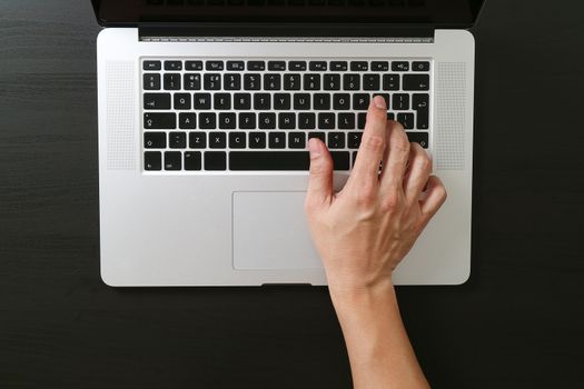 top view of businessman typing keyboard with laptop computer on wooden desk in modern office,black and white 