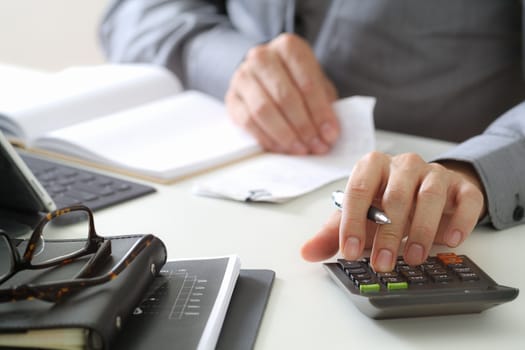 businessman hand working with finances about cost and calculator and latop with mobile phone on withe desk in modern office 