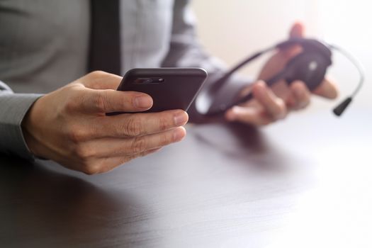 businessman using VOIP headset with mobile phone and concept communication call center on wooden desk