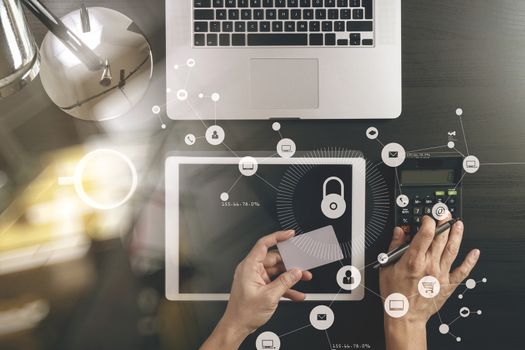 cyber security concept.Top view of hands working with calculator and laptop and credit card and tablet computer on dark wooden table background