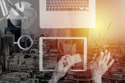 Internet shopping concept.Top view of hands working with calculator and laptop and credit card and tablet computer on dark wooden table background with buildings exposure