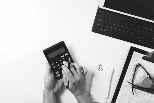 top view of businessman hand working with finances about cost and calculator and latop with mobile phone on withe desk in modern office,black and white