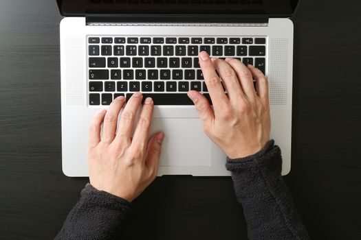 top view of businessman typing keyboard with laptop computer on wooden desk in modern office 