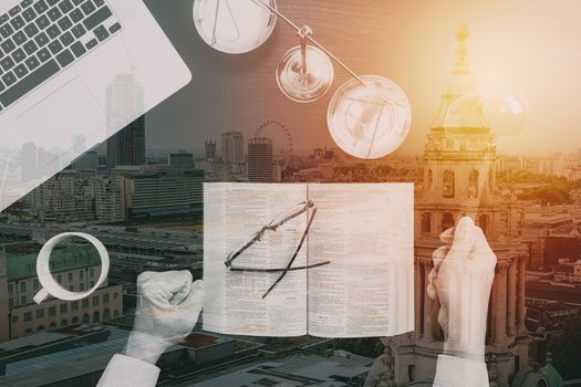 justice and law concept.Top view of Male judge hand in a courtroom with the gavel and brass scale and computer and open bible book on dark wood table with buildings exposure