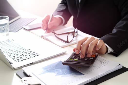 businessman hand working with finances about cost and calculator and latop with mobile phone on withe desk in modern office 