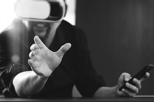 businessman wearing virtual reality goggles in modern office with mobile phone using with VR headset,black and white