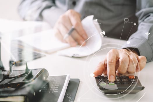 businessman hand working with finances about cost and calculator and latop with mobile phone on withe desk in modern office with VR icon diagram