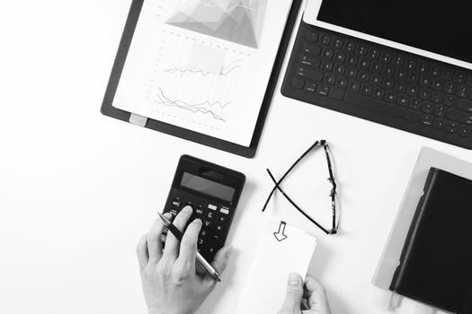 top view of businessman hand working with finances about cost and calculator and latop with mobile phone on withe desk in modern office,black and white 