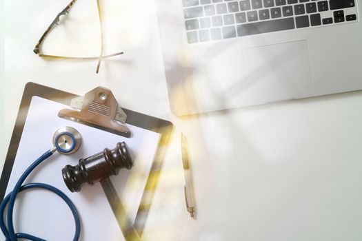 Dark Gavel With Medical Stethoscope near Laptop on white desk In Courtroom concept