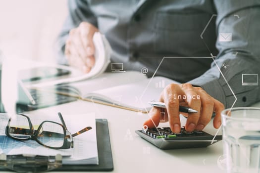 businessman hand working with finances about cost and calculator and latop with mobile phone on withe desk in modern office with VR icon diagram