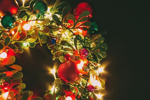 Greeting Season concept.Christmas wreath with decorative light on dark wood background