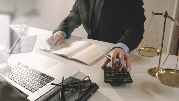 justice and law concept.businessman or lawyer or accountant working on accounts using a calculator and laptop computer and documents in modern office