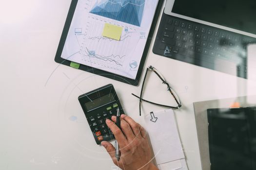 top view of businessman hand working with finances about cost and calculator and latop with mobile phone on withe desk in modern office with VR icon diagram