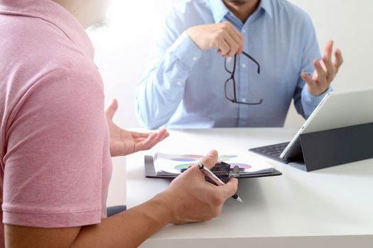 Businessmen working together on a document and using smart phone and digital tablet and laptop computer in modern office                                     