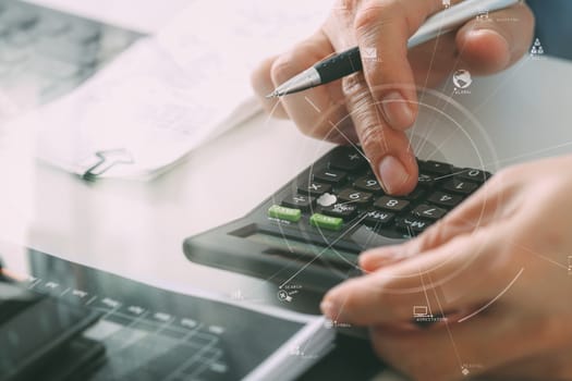 close up of businessman hand working with finances about cost and calculator and latop with mobile phone on withe desk in modern office with VR icon diagram