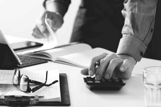 businessman hand working with finances about cost and calculator and latop with mobile phone on withe desk in modern office ,black and white