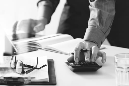 businessman hand working with finances about cost and calculator and latop with mobile phone on withe desk in modern office,black and white