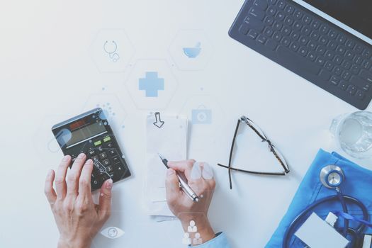 top view of Healthcare costs and fees concept.Hand of smart doctor used a calculator for medical costs in modern hospital with VR icon diagram