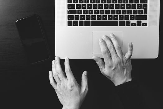 cyber security internet and networking concept.Businessman hand working mobile phone on laptop computer background,black and white