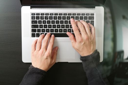 top view of businessman typing keyboard with laptop computer on wooden desk in modern office 