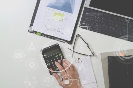 top view of businessman hand working with finances about cost and calculator and latop with mobile phone on withe desk in modern office with VR icon diagram