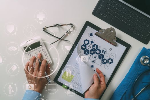 top view of Healthcare costs and fees concept.Hand of smart doctor used a calculator for medical costs in modern hospital with VR icon diagram