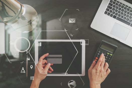 Internet shopping concept.Top view of hands working with laptop and credit card and tablet computer on dark wooden table background with Vr diagram