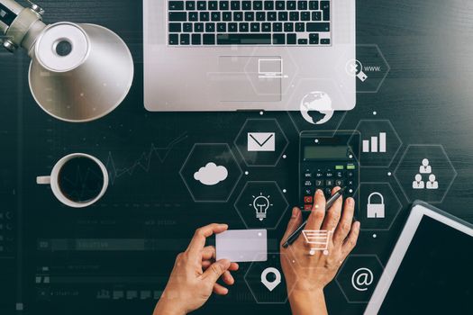 Internet shopping concept.Top view of hands working with calculator and laptop and credit card and tablet computer on dark wooden table background with Vr diagram