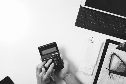 top view of businessman hand working with finances about cost and calculator and latop with mobile phone on withe desk in modern office ,black and white