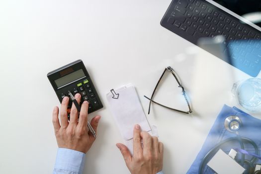 top view of Healthcare costs and fees concept.Hand of smart doctor used a calculator for medical costs in modern hospital 