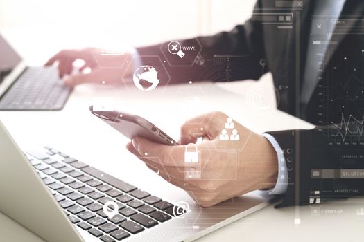 Hands of businessman using mobile phone in modern office with laptop and digital tablet computer with VR icon diagram