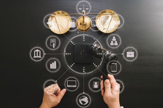 justice and law concept.Top view of Male judge hand in a courtroom with the gavel and brass scale on dark wood table with Vr diagram