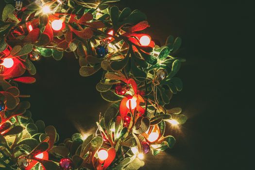 Greeting Season concept.Christmas wreath with decorative light on dark wood background