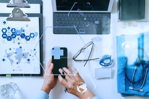 top view of smart medical doctor working with mobile phone and laptop computer and stethoscope on dark wooden desk with virtual reality icon diagram 