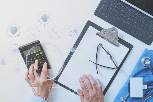 top view of Healthcare costs and fees concept.Hand of smart doctor used a calculator for medical costs in modern hospital with VR icon diagram