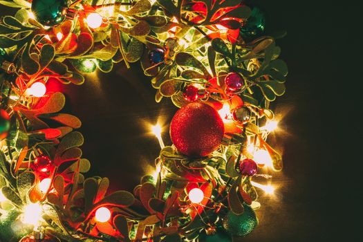 Greeting Season concept.Christmas wreath with decorative light on dark wood background