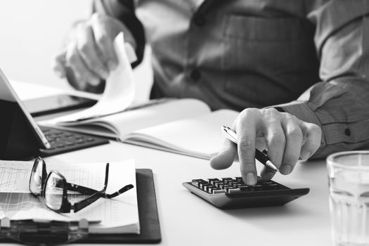 businessman hand working with finances about cost and calculator and latop with mobile phone on withe desk in modern office,black and white