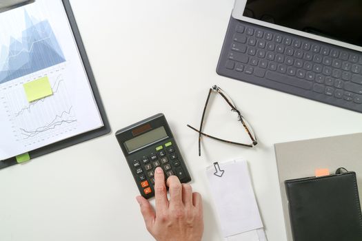 top view of businessman hand working with finances about cost and calculator and latop with mobile phone on withe desk in modern office 