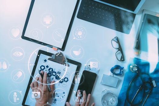 top view of smart medical doctor working with mobile phone and laptop computer and stethoscope on dark wooden desk with virtual reality icon diagram 