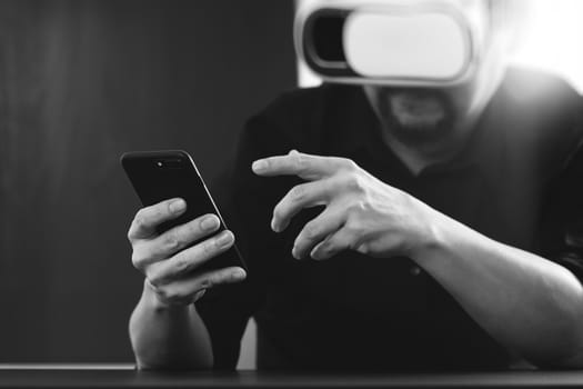 businessman wearing virtual reality goggles in modern office with mobile phone using with VR headset,black and white