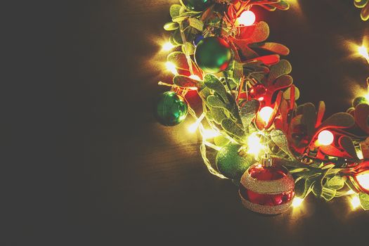 Greeting Season concept.Christmas wreath with decorative light on dark wood background