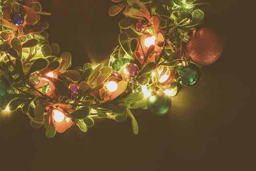 Greeting Season concept.Christmas wreath with decorative light on dark wood background