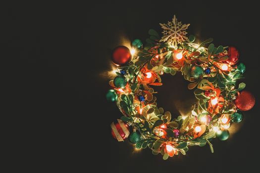 Greeting Season concept.Christmas wreath with decorative light on dark wood background