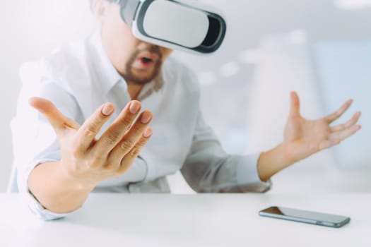 businessman wearing virtual reality goggles in modern office with mobile phone using with VR headset 